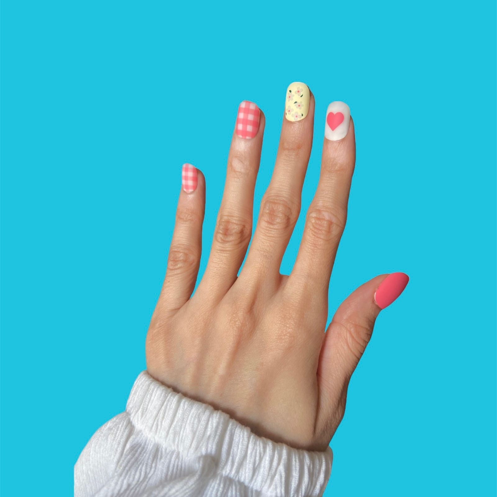 Close-up of press-on nails featuring a delicate and vibrant flower print design in various shades. The floral pattern includes intricate details, adding a touch of natural beauty to the nails.